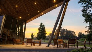 An outdoor seating area with wooden benches and a glass building in the background. - Idyllic Nature Lodge by Belvilla (Antoing)