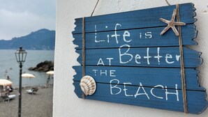 Ein hölzernes Schild mit dem Schriftzug 'Life is better at the beach' und einer Sternfisch-Dekoration.