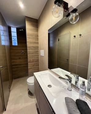 A modern bathroom with a large sink, mirror, and wooden panel wall. - Casa Castagna a' Mare (Salerno)