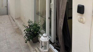 Ein Balkon mit Blumentöpfen, einer Laterne und einer Schiebetür.
