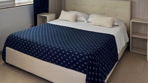 Ein Schlafzimmer mit Bett, Vorhängen am Fenster, einem Nachttisch und einem eingebauten Kleiderschrank.
