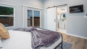 Ein Schlafzimmer mit Bett, einer Schiebetür zum Badezimmer und einem an der Wand montierten Fernseher.