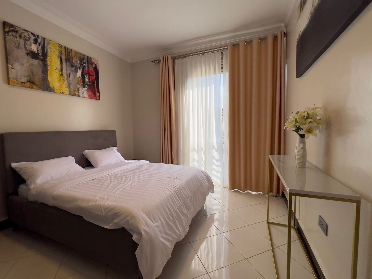 A neatly arranged bedroom with a bed, a bedside table, and a painting on the wall.