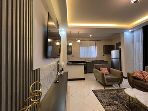 Una sala de estar moderna con un sofá, una mesa de centro y un televisor montado en la pared.