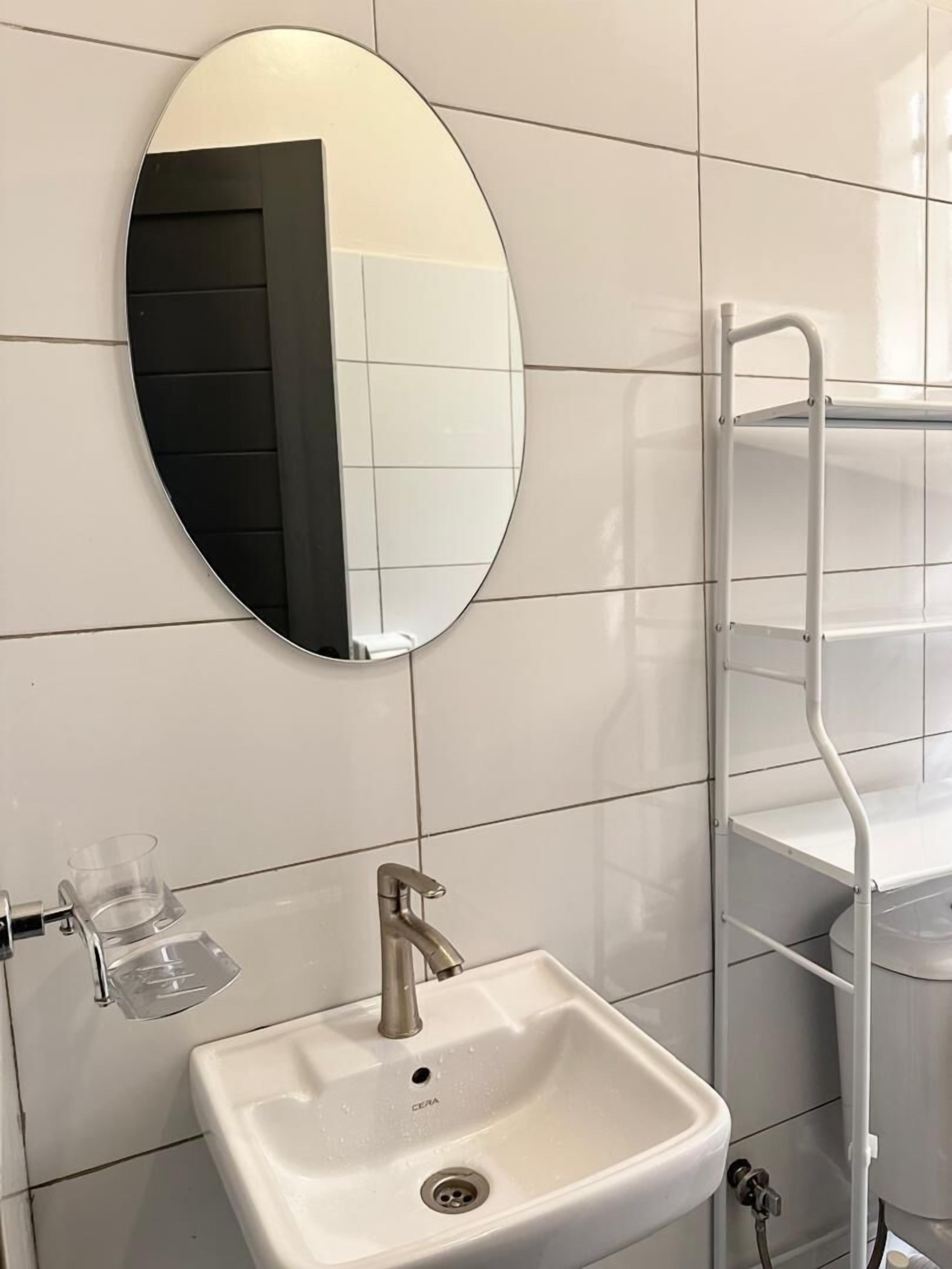 A bathroom with a white sink, a mirror, and a white tiled wall.
