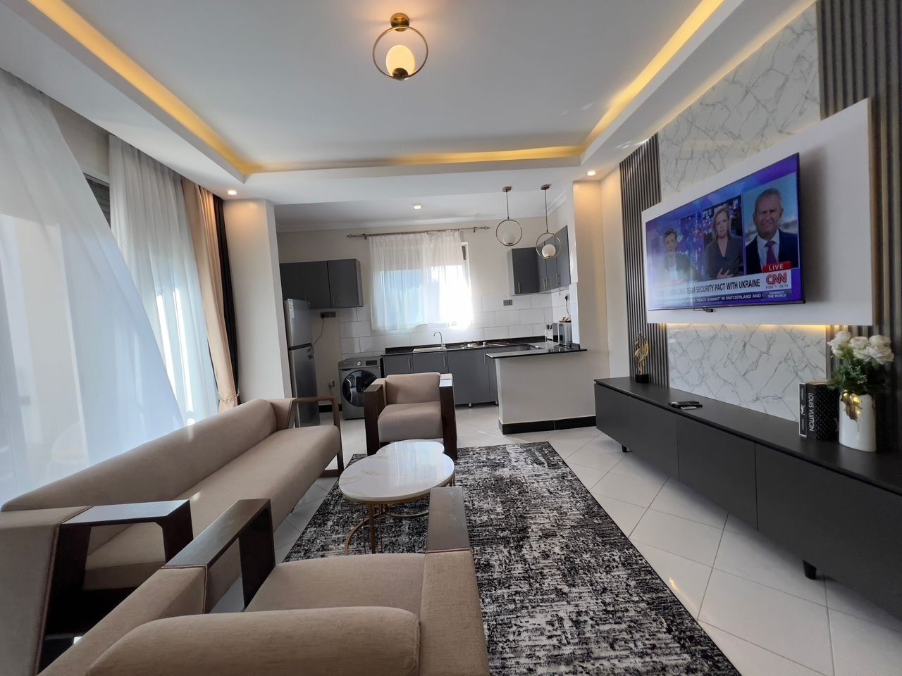 A modern living room with a sofa, a coffee table, and a TV mounted on the wall.