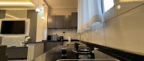 A modern kitchen with a built-in stove, a flat-screen TV, and a dining area with a table and chairs.