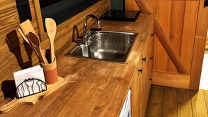 Una cocina de madera con un lavamanos, utensilios de madera y un ventanal.