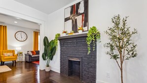 A living room with a fireplace, a sofa, a yellow armchair, and a large plant. - NEW ATL Bungalow-Sun Room-BBQ-King Bed-Fenced Yard (Atlanta)