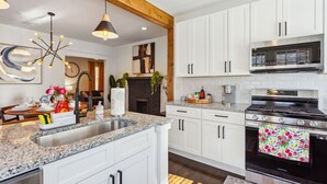 A modern kitchen with white cabinets, a granite countertop, a stainless steel stove, and a black oven. - NEW ATL Bungalow-Sun Room-BBQ-King Bed-Fenced Yard (Atlanta)