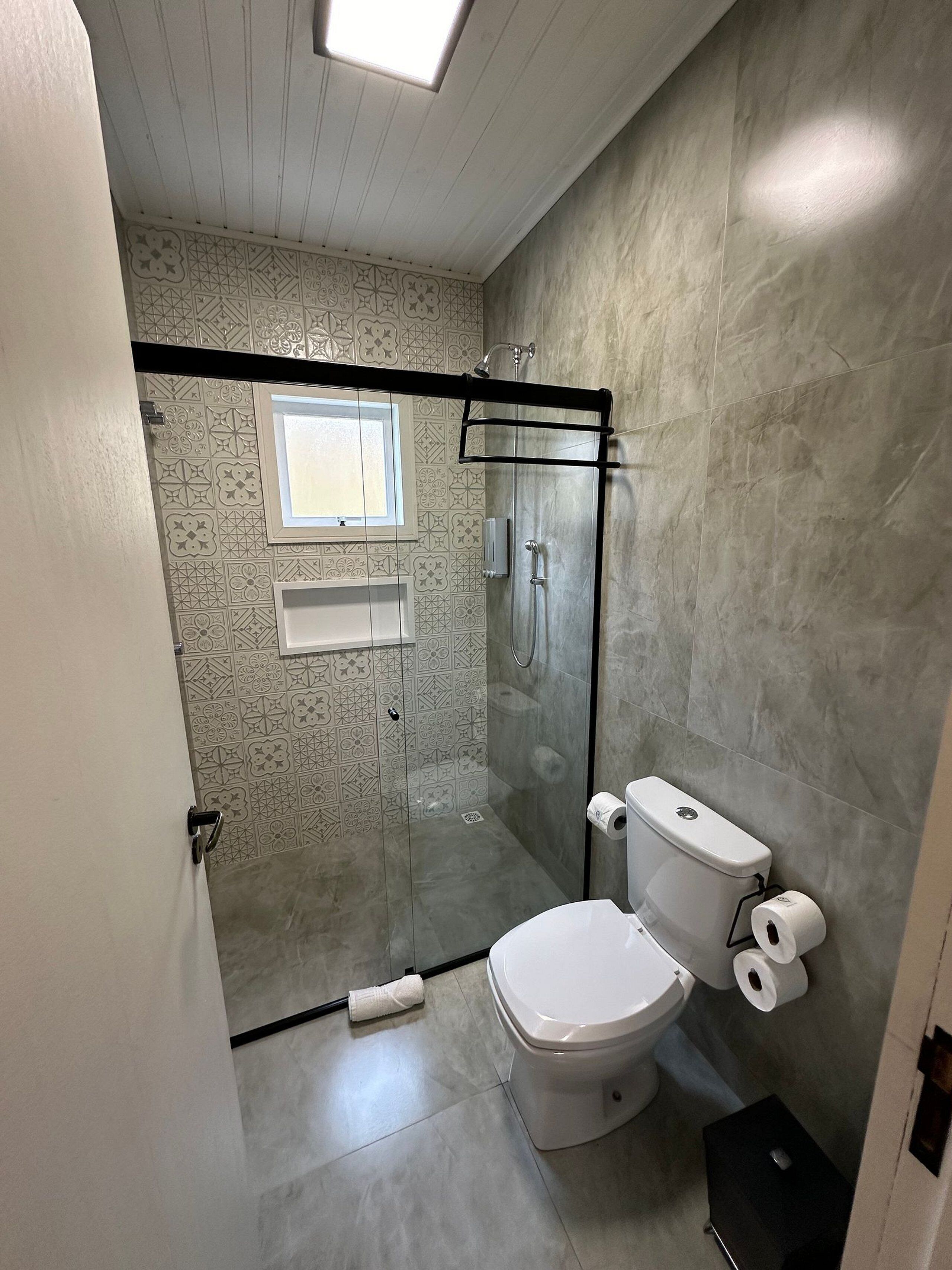 A bathroom with a glass-enclosed shower, a toilet, and a sink.