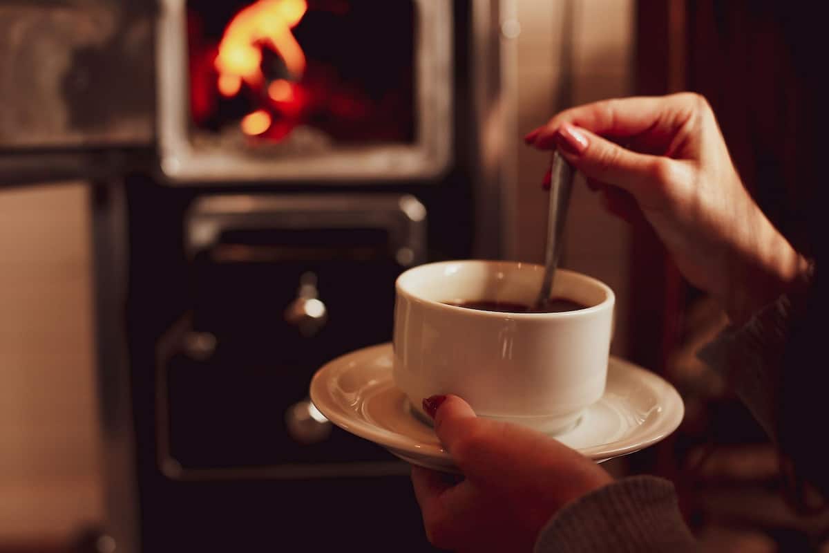 A person holding a cup of coffee on a saucer.