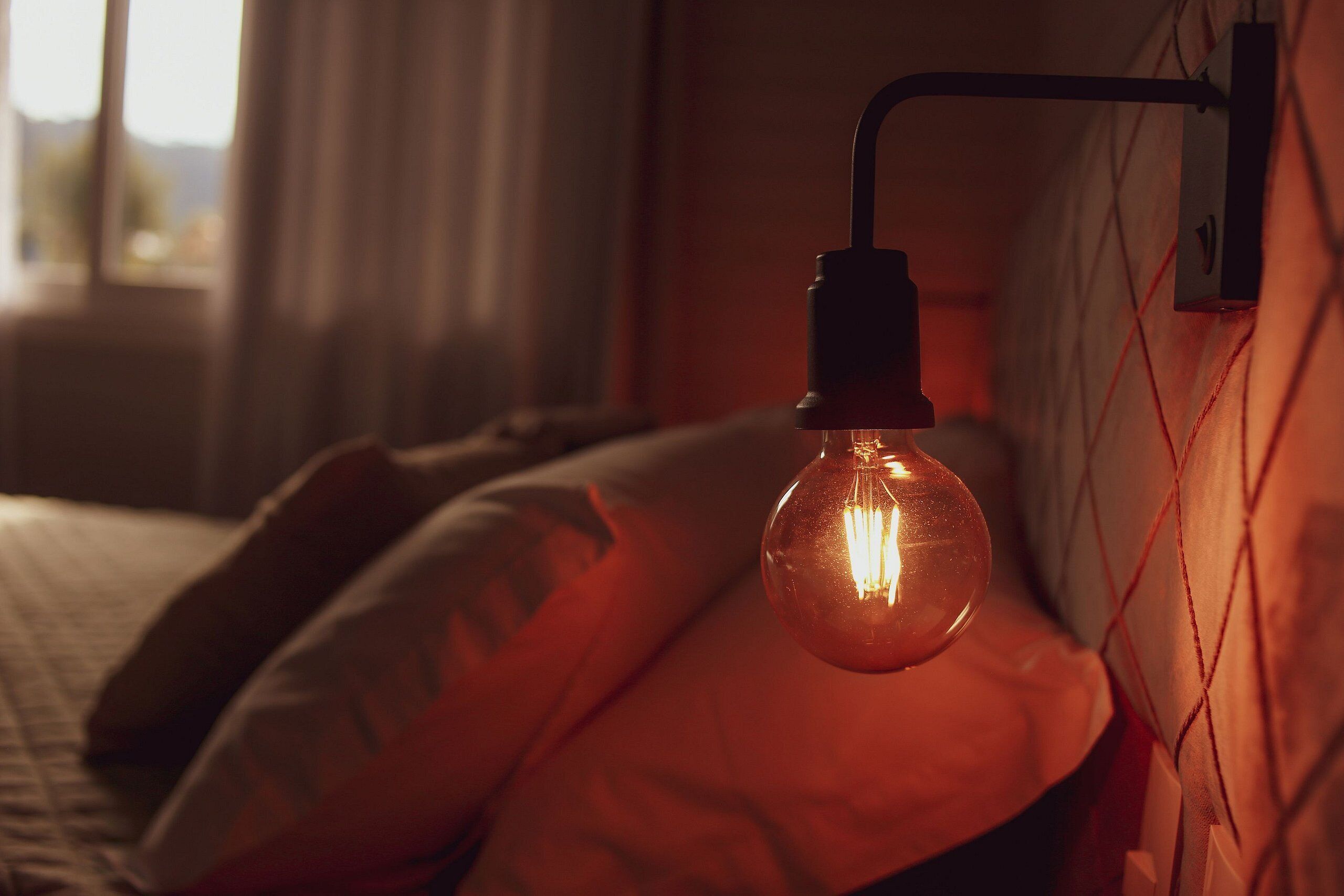 Un lit avec une suspension lumineuse.