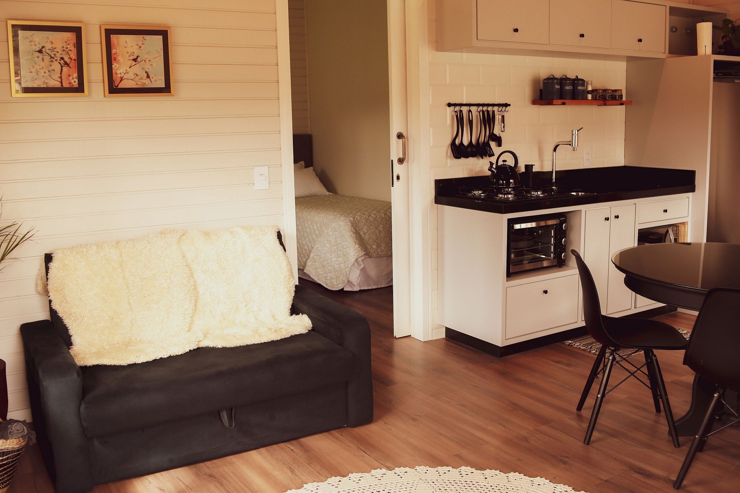 A compact living space with a black sofa, a small kitchenette, and a dining area.
