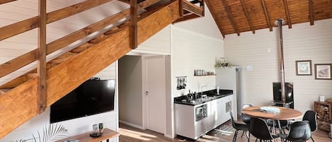 A spacious living area with a wooden staircase, a kitchen, and a dining area.