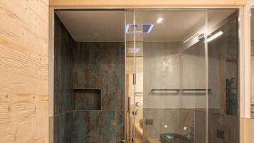 Un bagno moderno con cabina doccia in vetro, rivestimento in legno e lavabo in pietra.