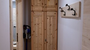 A hallway with wooden flooring, a wooden wardrobe, and a wall-mounted hookboard. - Pelmo Mountain Lodge (Borca di Cadore)
