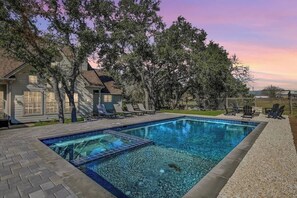 A rectangular swimming pool with a tiled edge, surrounded by a pebble border. - Luxury Dripping Springs Home-Pool&Hot-Tub Firepit! (Dripping Springs)