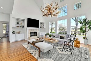 A spacious living room with a fireplace, a large chandelier, and a comfortable seating area. - Luxury Dripping Springs Home-Pool&Hot-Tub Firepit! (Dripping Springs)