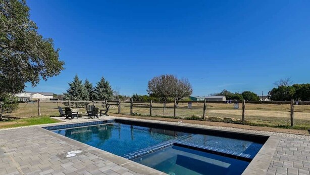 Una piscina rectangular con borde de azulejos, rodeada por un patio de ladrillo.