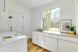 A modern kitchen with white cabinets, a large window, and a sink.