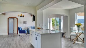 Une cuisine spacieuse dotée d’un îlot central, un coin repas avec une table en verre et une vue sur l’extérieur.