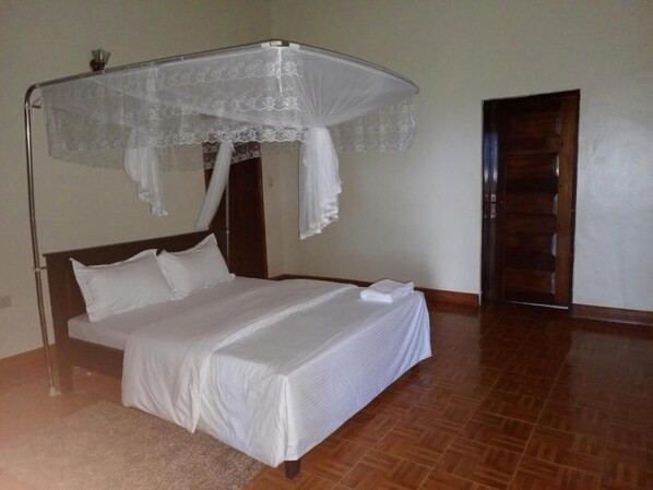 Cozy retreat with a single bed and canopy bedspread, featuring a tiled floor and wooden door.