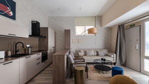 Una cucina moderna con isola centrale, un'area pranzo con tavolo rotondo e un soggiorno con divano e tavolino.