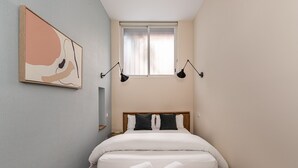 Una camera da letto con un letto, due abat-jour, una finestra e un’opera d’arte appesa al muro.