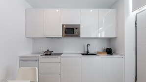 A modern kitchen with white cabinetry, a built-in microwave, a coffee maker, and a dishwasher. - Waou Coosy II Retiro (Madrid)