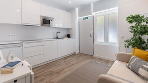 A modern kitchen with white cabinetry, a built-in microwave, and a sink. There's a door marked "SALIDA" indicating an exit. - Waou Coosy II Retiro (Madrid)