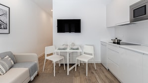 A modern, compact living space with a kitchenette, a dining area, and a sofa. - Waou Coosy II Retiro (Madrid)