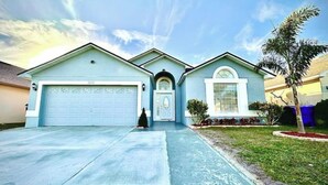 A two-story house with a garage, a front entrance with a small porch, and a well-maintained lawn. - Comfy Home Near Theme Parks (Kissimmee)