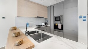 Une cuisine moderne dotée d’un plan de travail en marbre, d’appareils électroménagers en acier inoxydable et de meubles de rangement en bois.