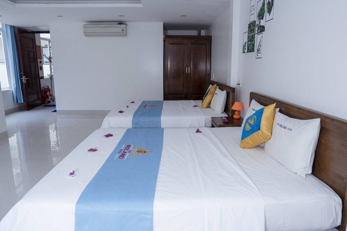Ein Hotelzimmer mit zwei Betten, einem Kleiderschrank und einem Badezimmer im Hintergrund.