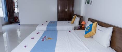 A hotel room with two beds, a wardrobe, and a bathroom visible in the background.