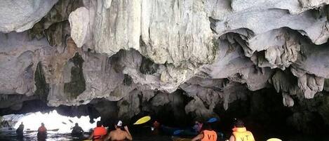 People kayaking in a cave with stalactites.