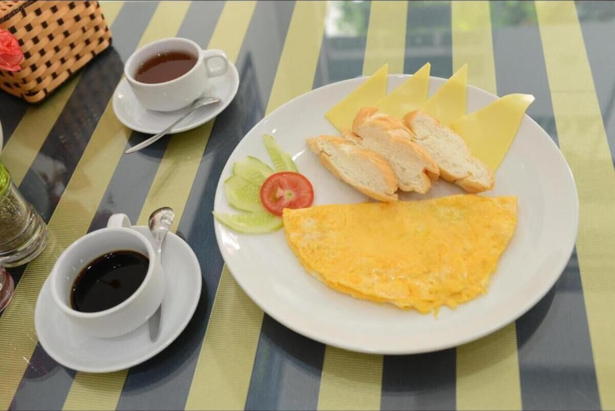 A plate with an omelette, bread, and vegetables on a striped tablecloth.