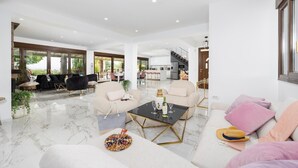 A spacious living area with a marble floor, a black coffee table, and a sofa with a pink pillow. - Villa Wild Willow - Six Bedroom Villa, Sleeps 12 (Potamos)