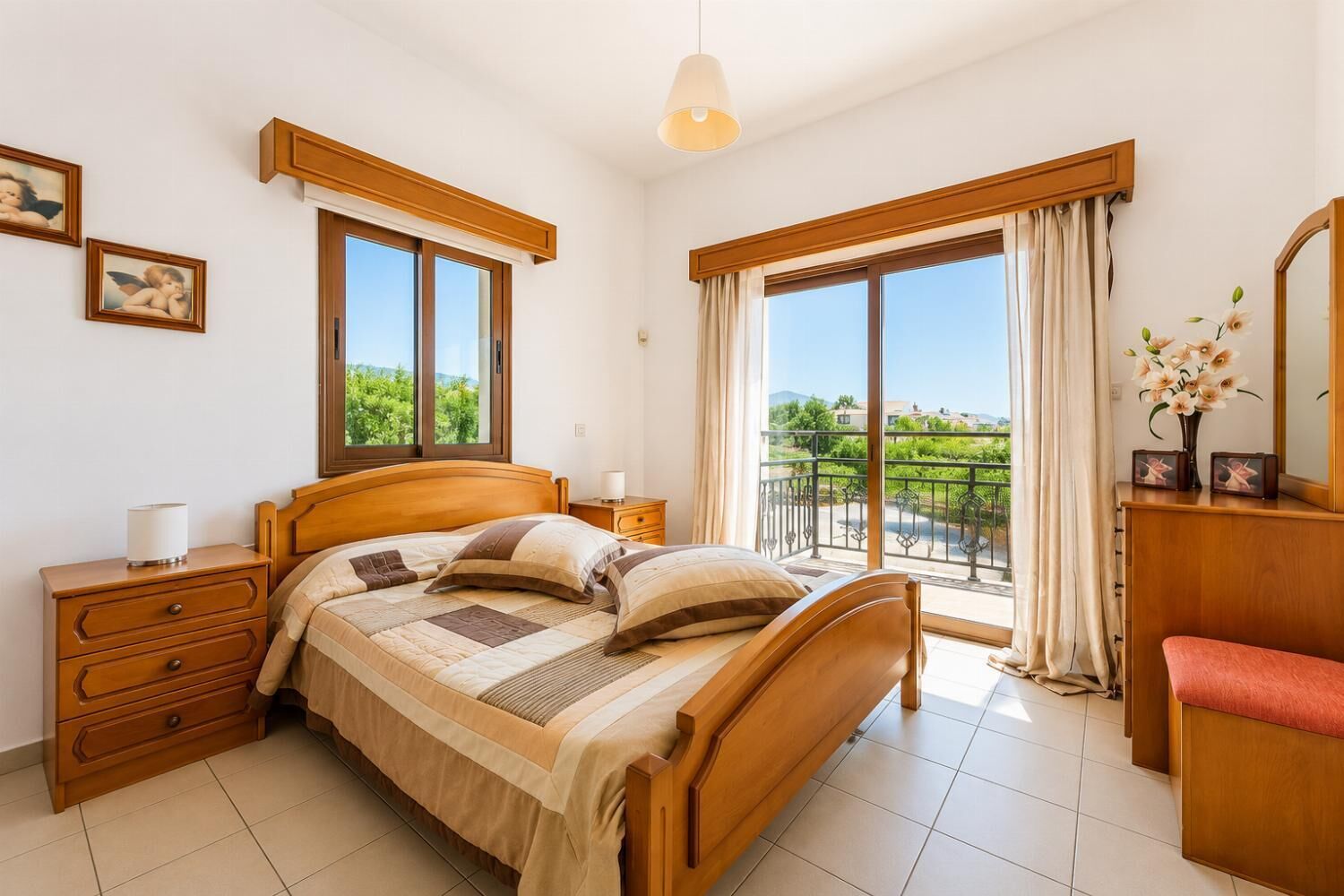 A bedroom with a wooden bed, a nightstand, a dresser, and a balcony with a view.