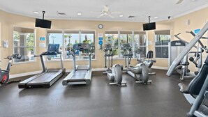 Un gimnasio con cintas de correr, elípticas y equipo de pesas.