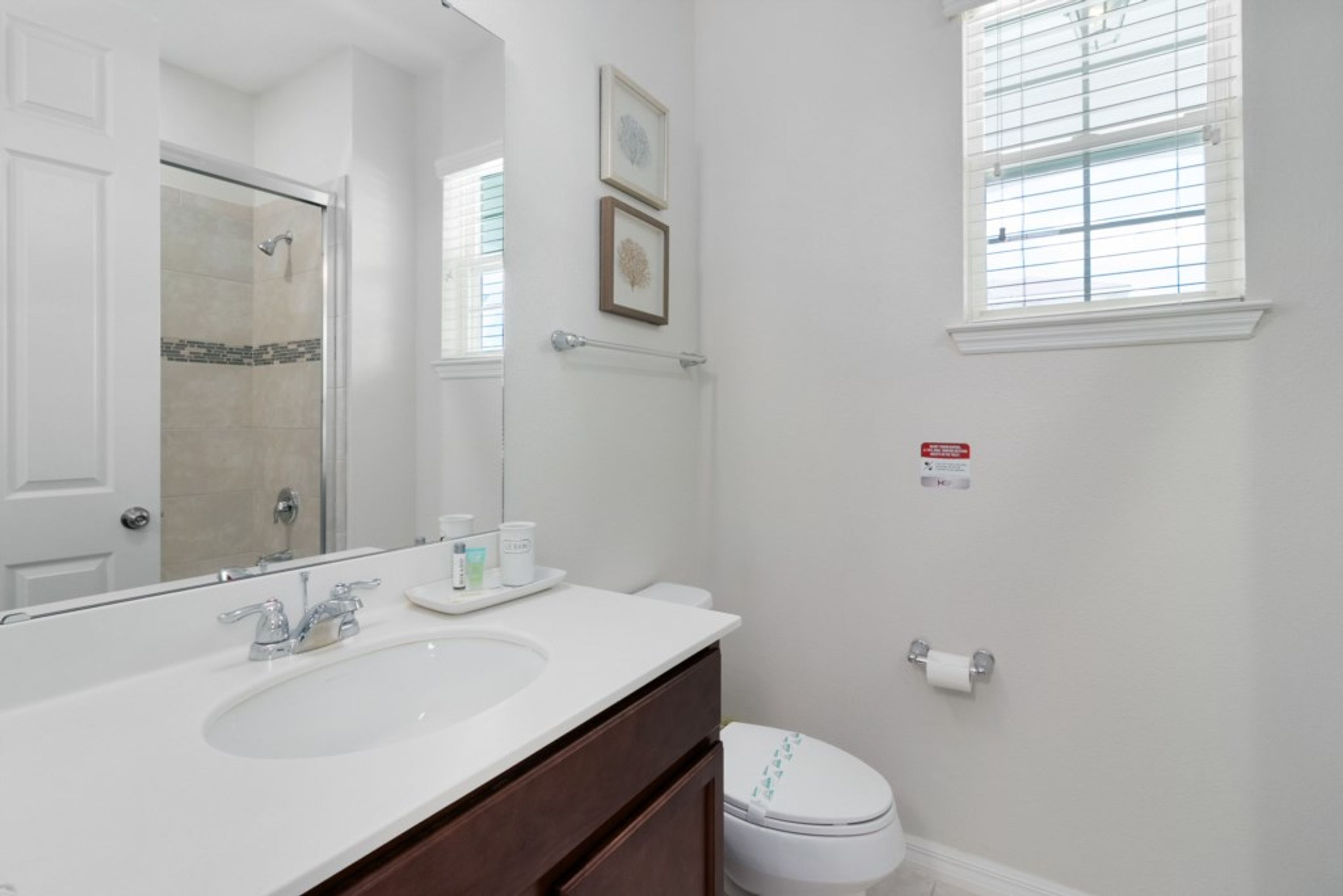 A bathroom with a white sink, a mirror, a toilet, and a shower.