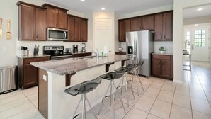 A modern kitchen with granite countertops, stainless steel appliances, and wooden cabinets. - Incredible Resort 4 bed Pool Spa Home (Kissimmee)