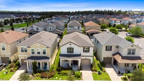 A residential area with multiple two-story houses, each with a front garage, well-maintained lawns, and a clear sky. - Incredible Resort 4 bed Pool Spa Home (Kissimmee)