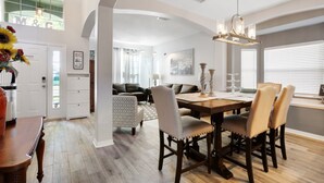 Un salon spacieux avec une table à manger en bois, des sièges confortables et un lustre.