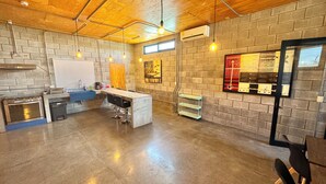 A modern kitchen with a marble island, a built-in oven, and a sink. There are hanging lights and a brick wall.