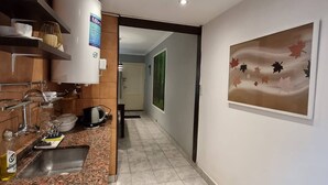 Eine moderne Küche mit Granit Arbeitsplatten, einem Gasherd, einer Kaffeemaschine und einem Fliesenboden.