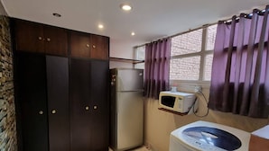 Eine kleine Küche mit Kühlschrank, Mikrowelle und Waschmaschine.