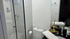 A bathroom with a glass shower enclosure, a toilet, and a sink with a mirror. - Studio 309 WBE São Paulo prx PUC Allianz (São Paulo)