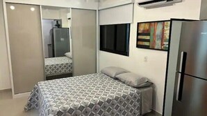 A bedroom with a bed, a wardrobe, a refrigerator, and a painting on the wall. - Studio 309 WBE São Paulo prx PUC Allianz (São Paulo)